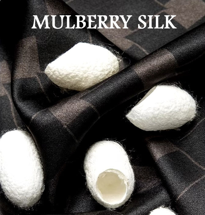 Mulberry silk fabric in deep brown with a geometric rhombus mesh design, held and draped alongside white silk cocoons to highlight its natural origin and luxurious texture. From Borcelleclothes.