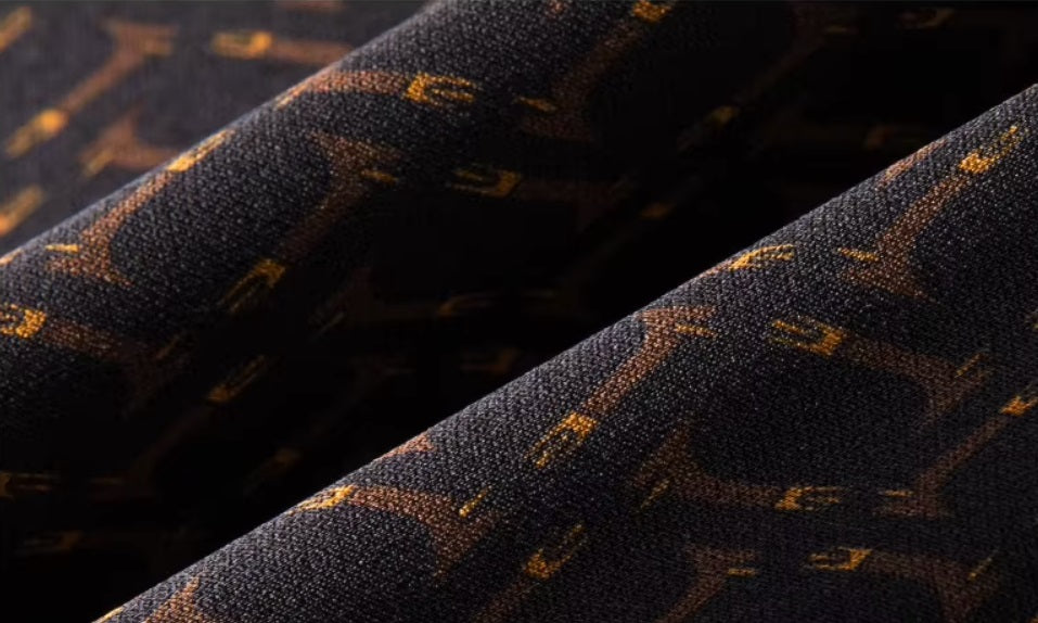 The fabric is folded to highlight its weaving and detailed geometric design with vibrant orange accents of the men's Mulberry silk shirt in English Walnut. From Borcelleclothes.
