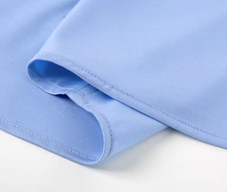 Detailed stitching and textured fabric on the bottom of the Men's 100% Mulberry silk shirt in solid Tropical Blue, featuring a pointed collar, single-breasted front, and a modern tailored silhouette. The shirt offers comfort, elegance, and a smooth, breathable texture. From Borcelleclothes.