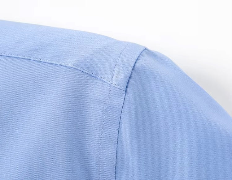Detailed stitching and textured fabric on the shoulder of the Men's 100% Mulberry silk shirt in solid Tropical Blue, featuring a pointed collar, single-breasted front, and a modern tailored silhouette. The shirt offers comfort, elegance, and a smooth, breathable texture. From Borcelleclothes.