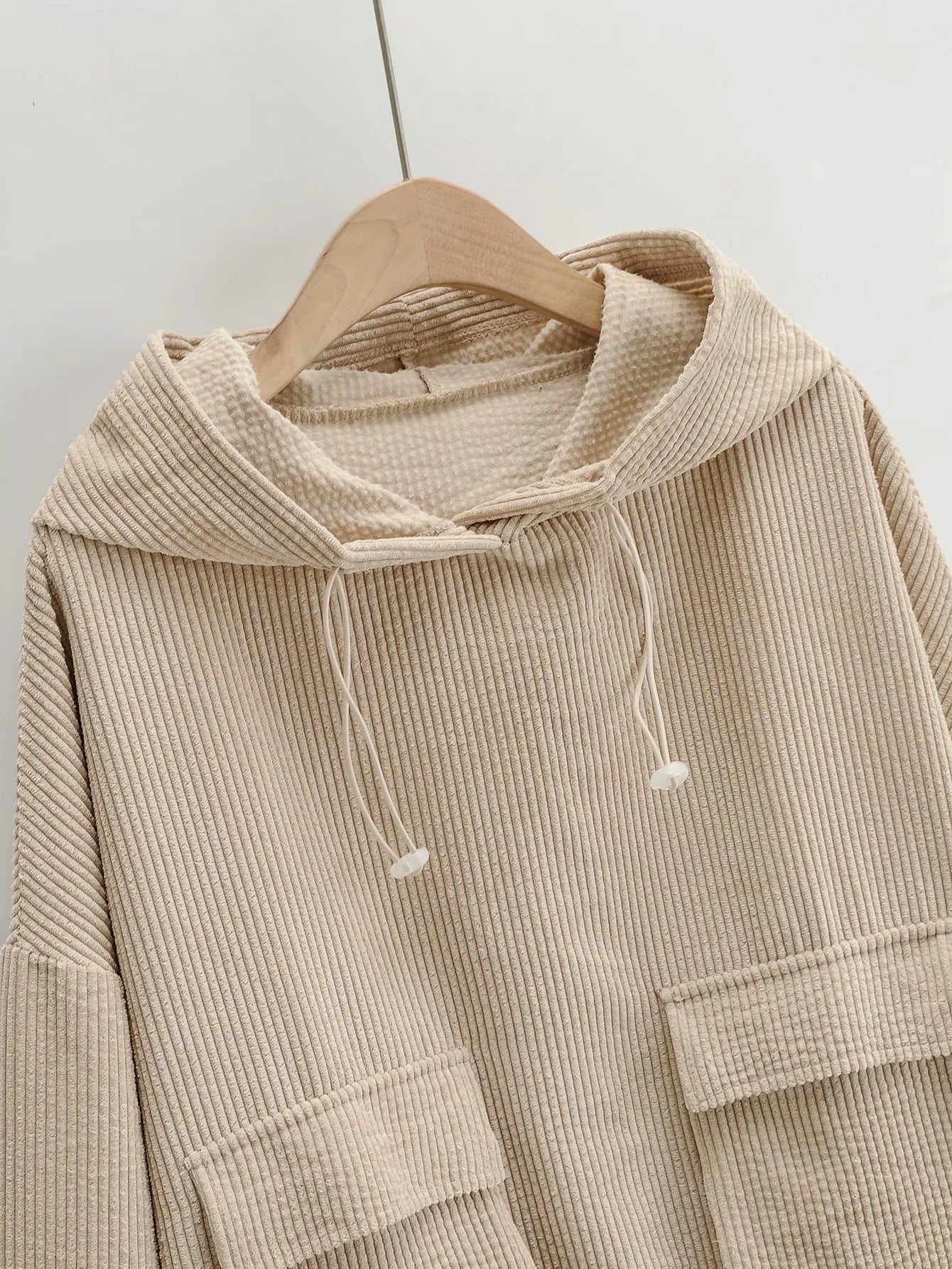 The top section of Women's Wide Wale Corduroy Sweatshirt in Coral Reef, designed with cargo flap pockets, drawstring hood, and elastic ribbed cuffs and waistband for a relaxed, stylish fit. From Borcelleclothes.