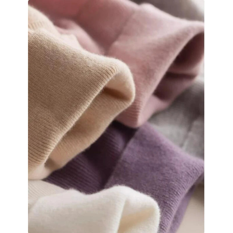 A pile of Alashan cashmere turtleneck sweaters in various colors, showcasing their plush texture and rich hues, Borcelleclothes.
