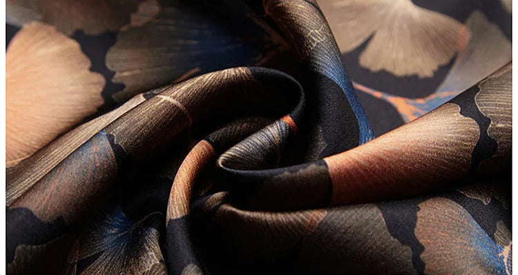 Spiral-folded detail of the Ginkgo silk shirt fabric, with interwoven leaves in earthy tones on a black silk background. From Borcelleclothes.