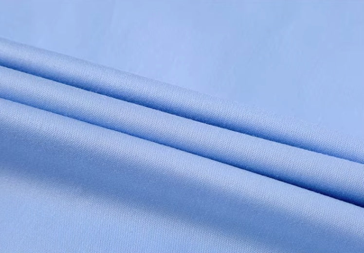 Folded fabric of a Men's 100% Mulberry silk shirt in solid Tropical Blue, showcasing luxurious draping. From Borcelleclothes.