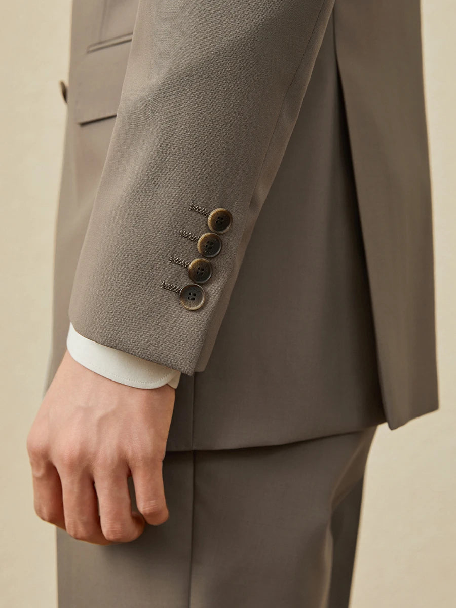 Model turned, sleeve placket of the Almond Frost blazer visible with horn buttons. From Borcelleclothes.