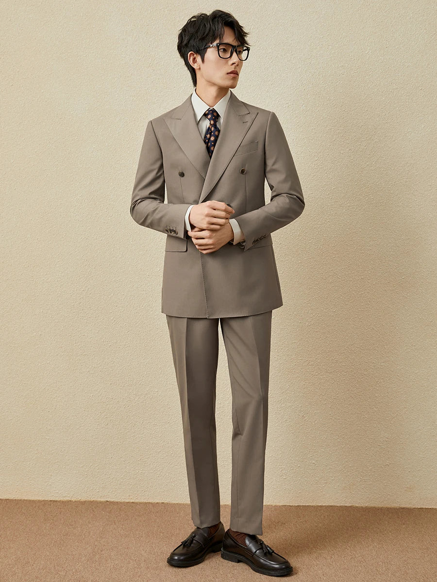 Model adjusting shirt cuff while wearing the Almond Frost suit, highlighting ease within structure. From Borcelleclothes.