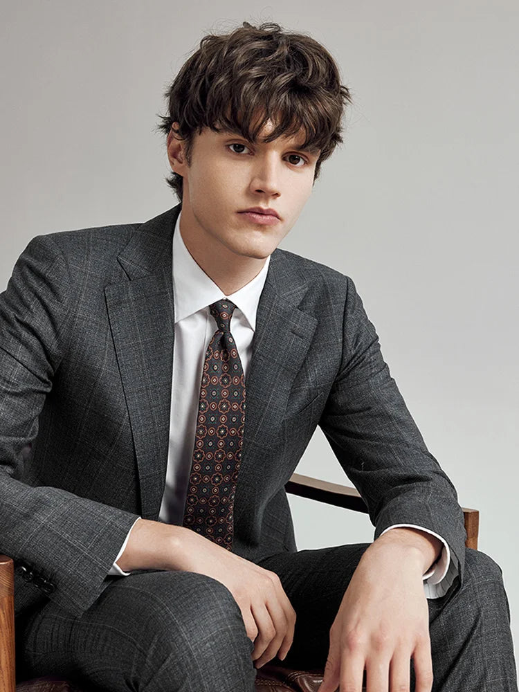 Model seated in the Borcelleclothes Men's Bright Grey 3-Piece Plaid Suit, highlighting the suit's versatility and refined plaid design.