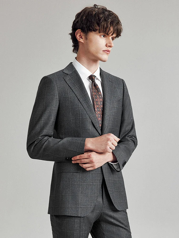 Model in the Borcelleclothes Men's Bright Grey 3-Piece Plaid Suit, gently touching the sleeve placket, emphasizing the detailed craftsmanship of the blazer.