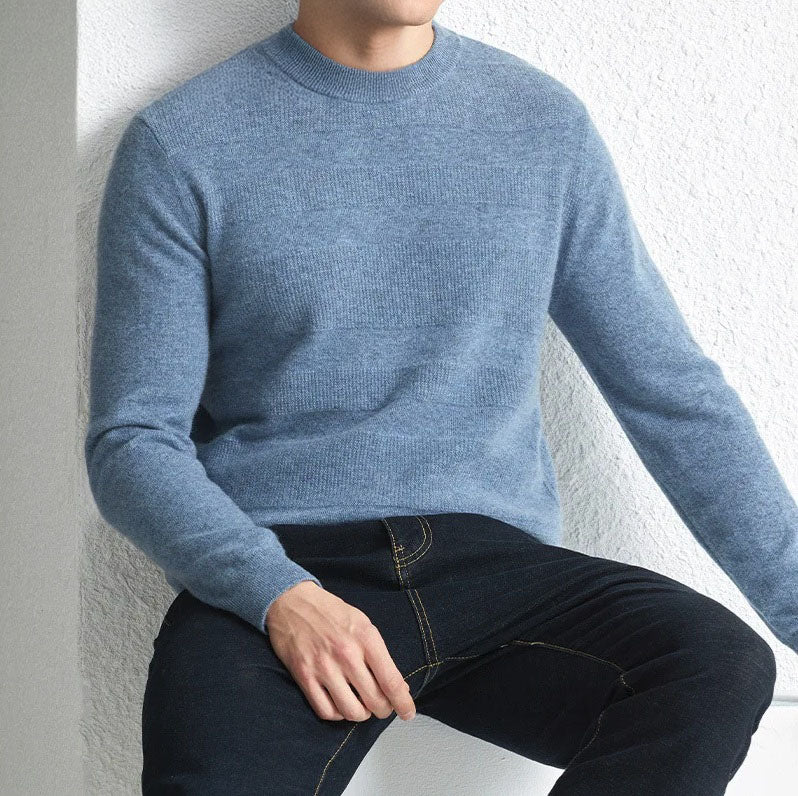 Model wearing the Men's Cashmere Crew Neck Sweater in Rock Blue while sitting on a chair, showcasing its relaxed yet refined fit. From Borcelleclothes.