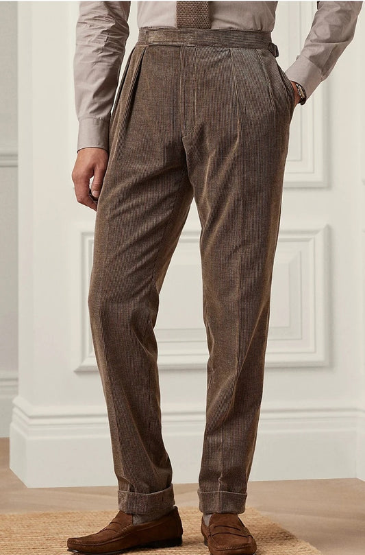 Man wears Cioccolato corduroy trousers, hand resting in pocket, highlighting front pleats and soft mid-wale texture. From Borcelleclothes.