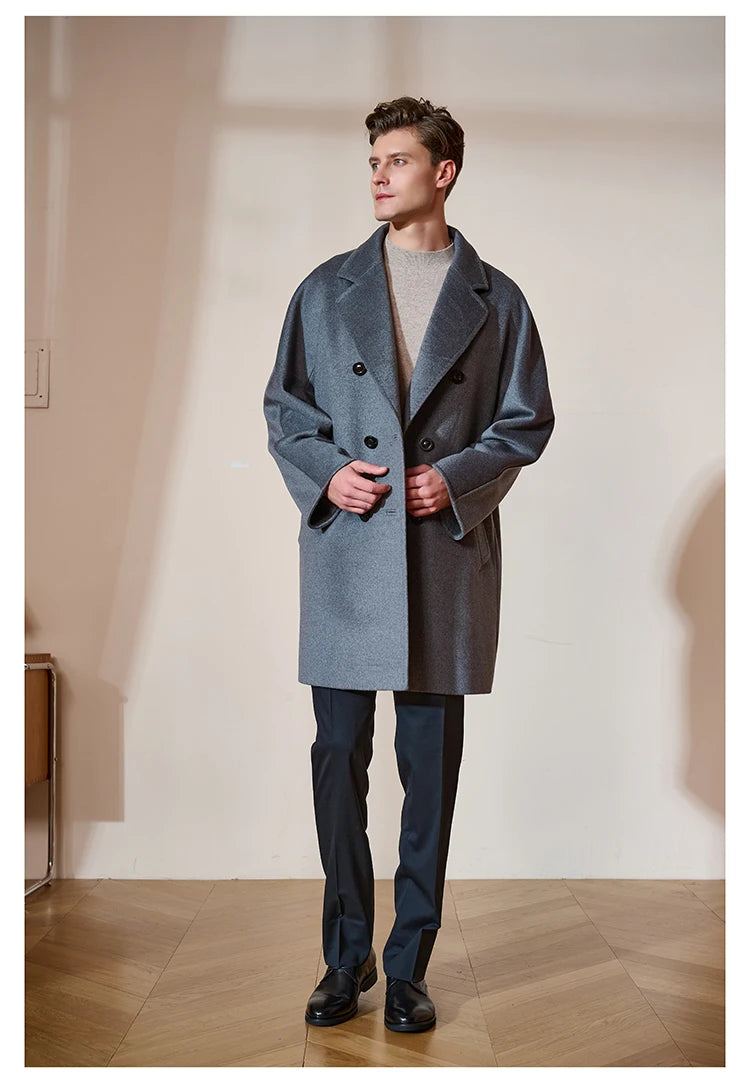 Model touching the front panels of the Men’s Double-Breasted Cashmere Coat in Light Slate Grey, highlighting the soft cashmere blend and fluid drape. From Borcelleclothes.