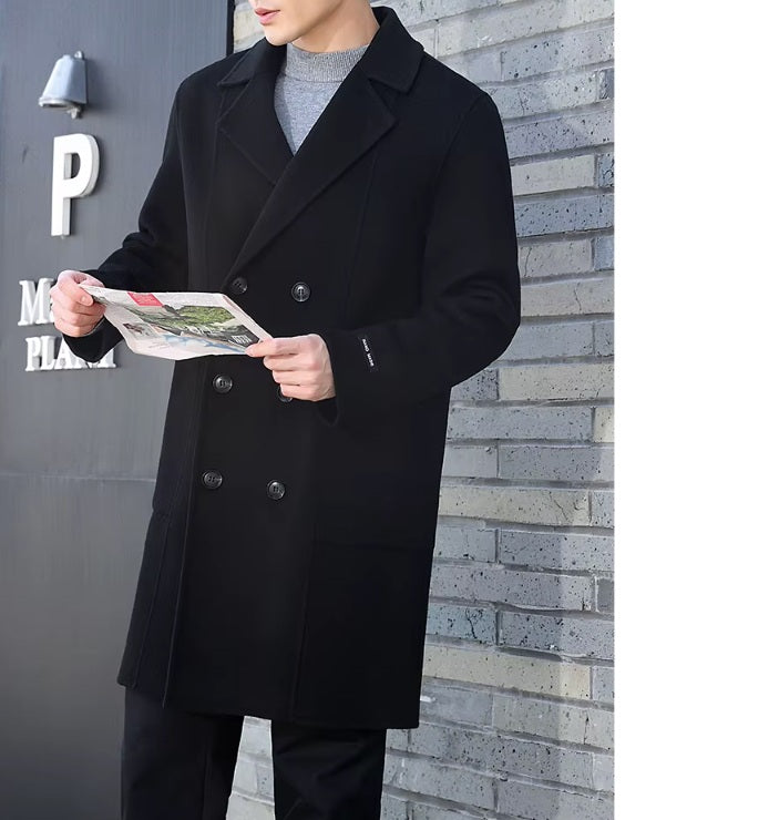 A model wearing the Men’s Double-Sided Wool Coat in Onyx, reading a newspaper, highlighting its polished and effortless sophistication. From Borcelleclothes.