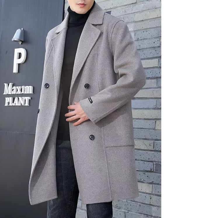 A model wearing the Men’s Double-Sided Wool Coat in Topaz, touching the front side, emphasizing its clean lines and tailored structure. From Borcelleclothes.