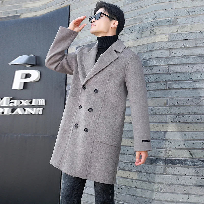 A model wearing the Men’s Double-Sided Wool Coat in Topaz, appearing to adjust glasses, adding a refined yet effortless styling detail. From Borcelleclothes.