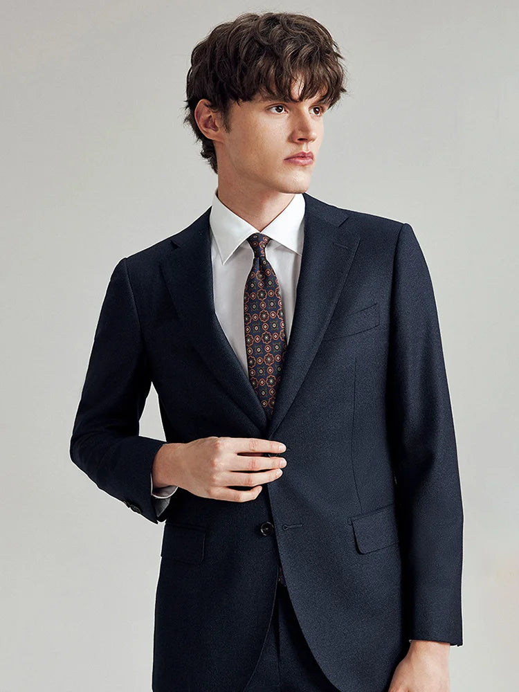 Model wearing the Borcelleclothes Men's Ebony Clay 3-Piece Suit, lightly touching the front edge of the blazer to showcase its tailored fit and elegant pinstripe details.