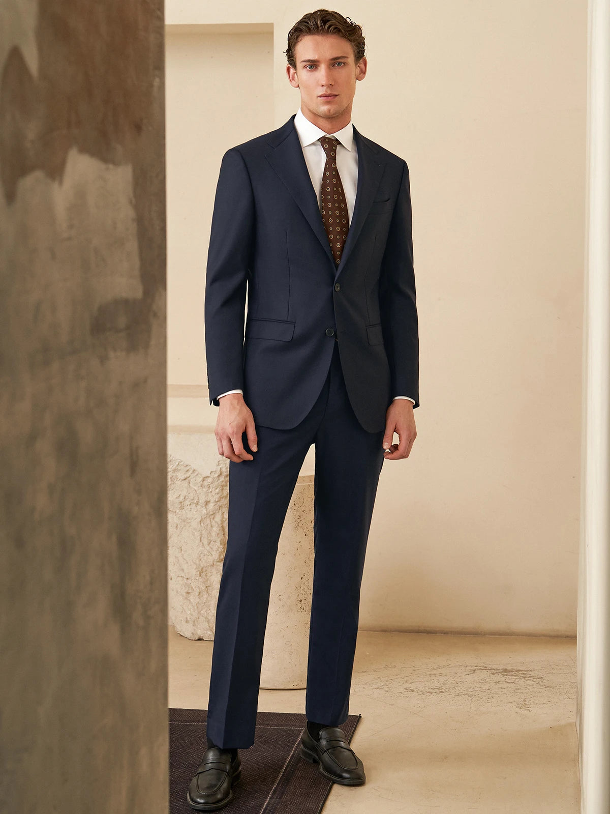 Model standing with straight arms in the Borcelleclothes Men's Ebony Clay Business Suit, emphasizing the clean lines and sharp tailoring of the blazer and pants.