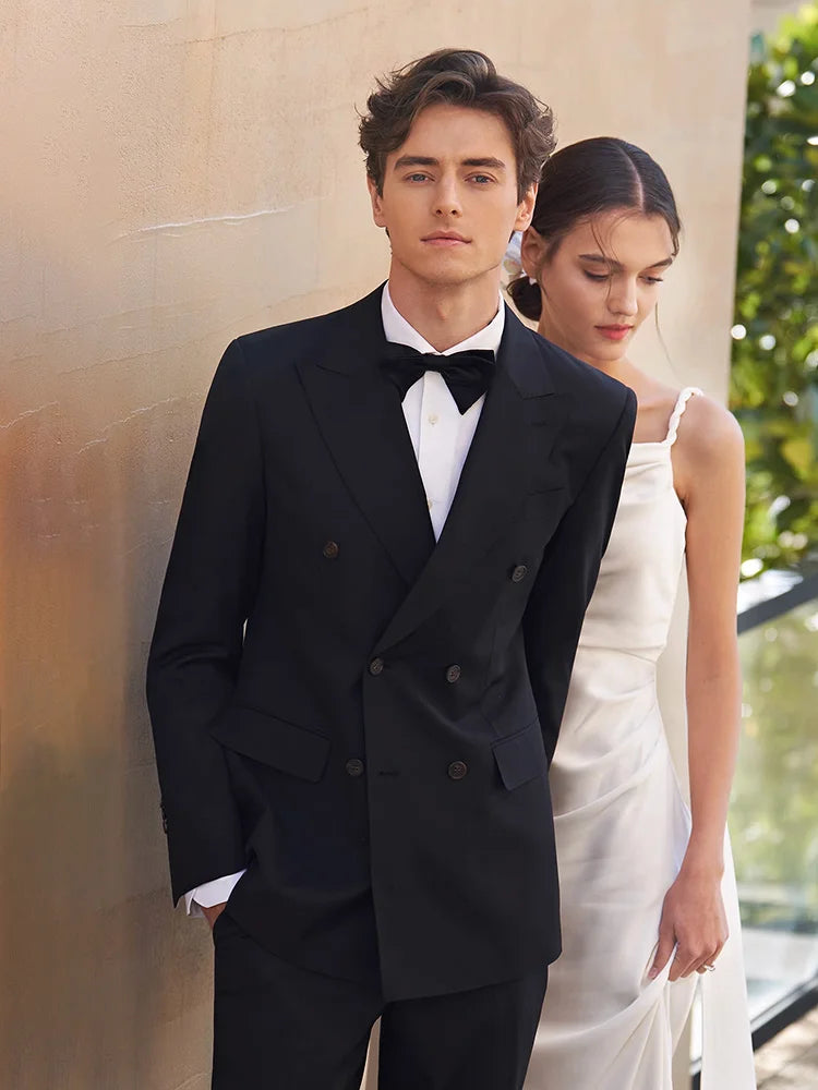 Ebony Clay suit with bride in the background — he’s not part of the story, yet shifts its direction. From Borcelleclothes.