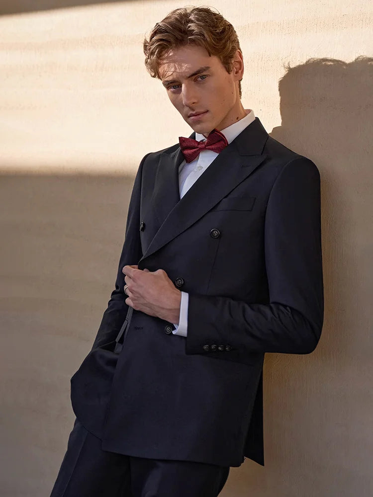 Model in formal wool suit, touching the blazer’s edge while watching straight ahead — a quiet, controlled stance. From Borcelleclothes.