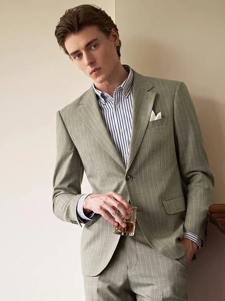 Model wearing the grey olive pinstripe suit, holding a glass of whiskey with a composed expression. From Borcelleclothes.