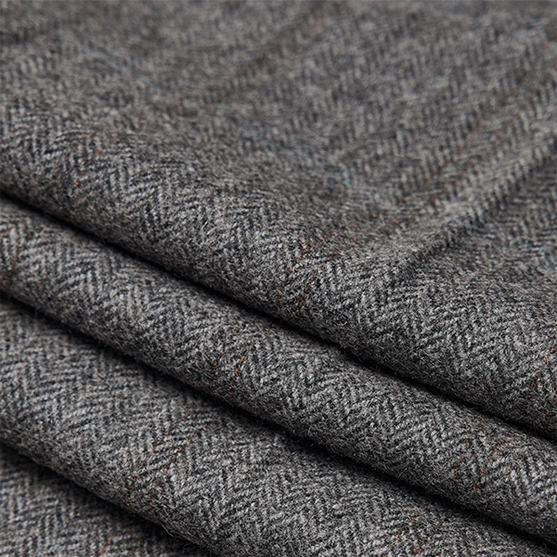 Folded fabric of cloudy grey herringbone wool trousers, showing weave texture and subtle brownish pinstripes. From Borcelleclothes.