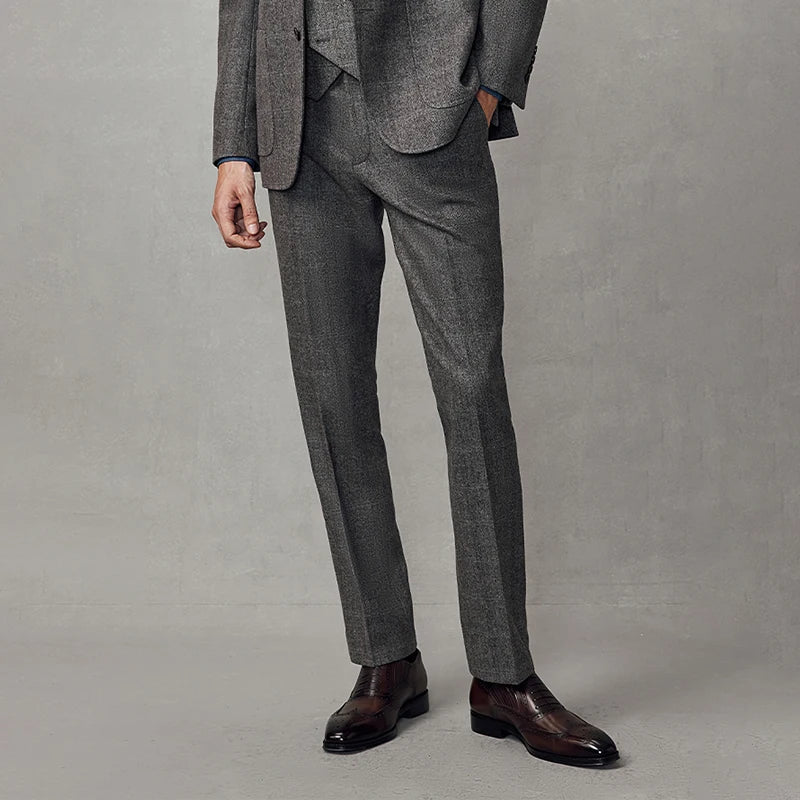 Model with one hand in pocket, highlighting front detail of cloudy grey herringbone trousers. From Borcelleclothes.