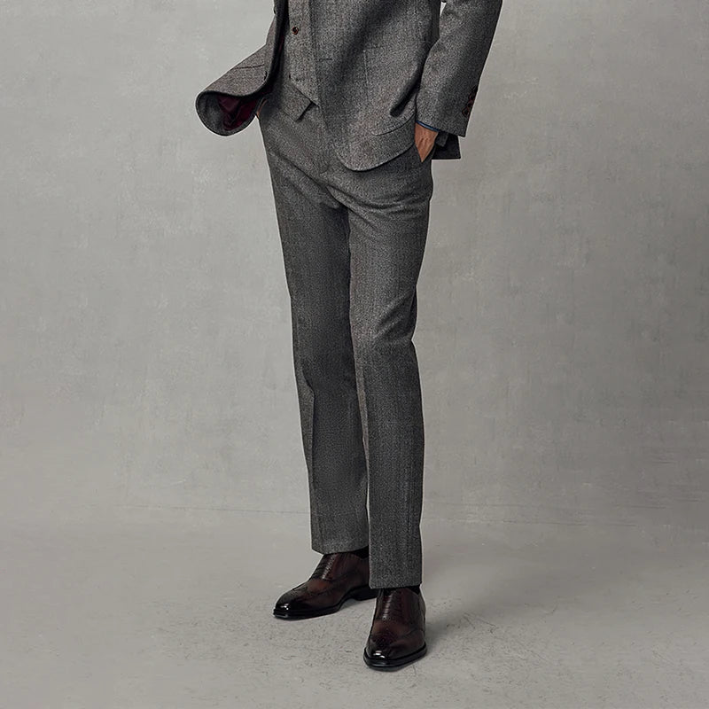 Model standing with hands in pockets, wearing slim herringbone trousers in cloudy grey. From Borcelleclothes.