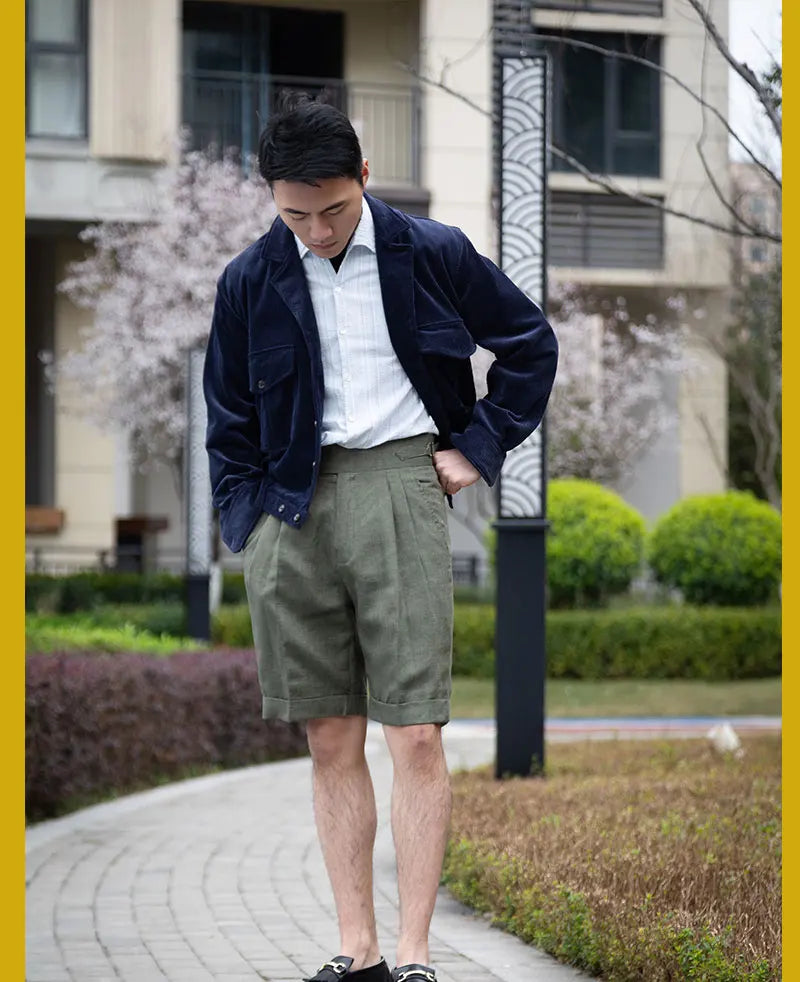 Model in sage green linen shorts standing with head lowered, highlighting the relaxed yet structured silhouette. From Borcelleclothes.
