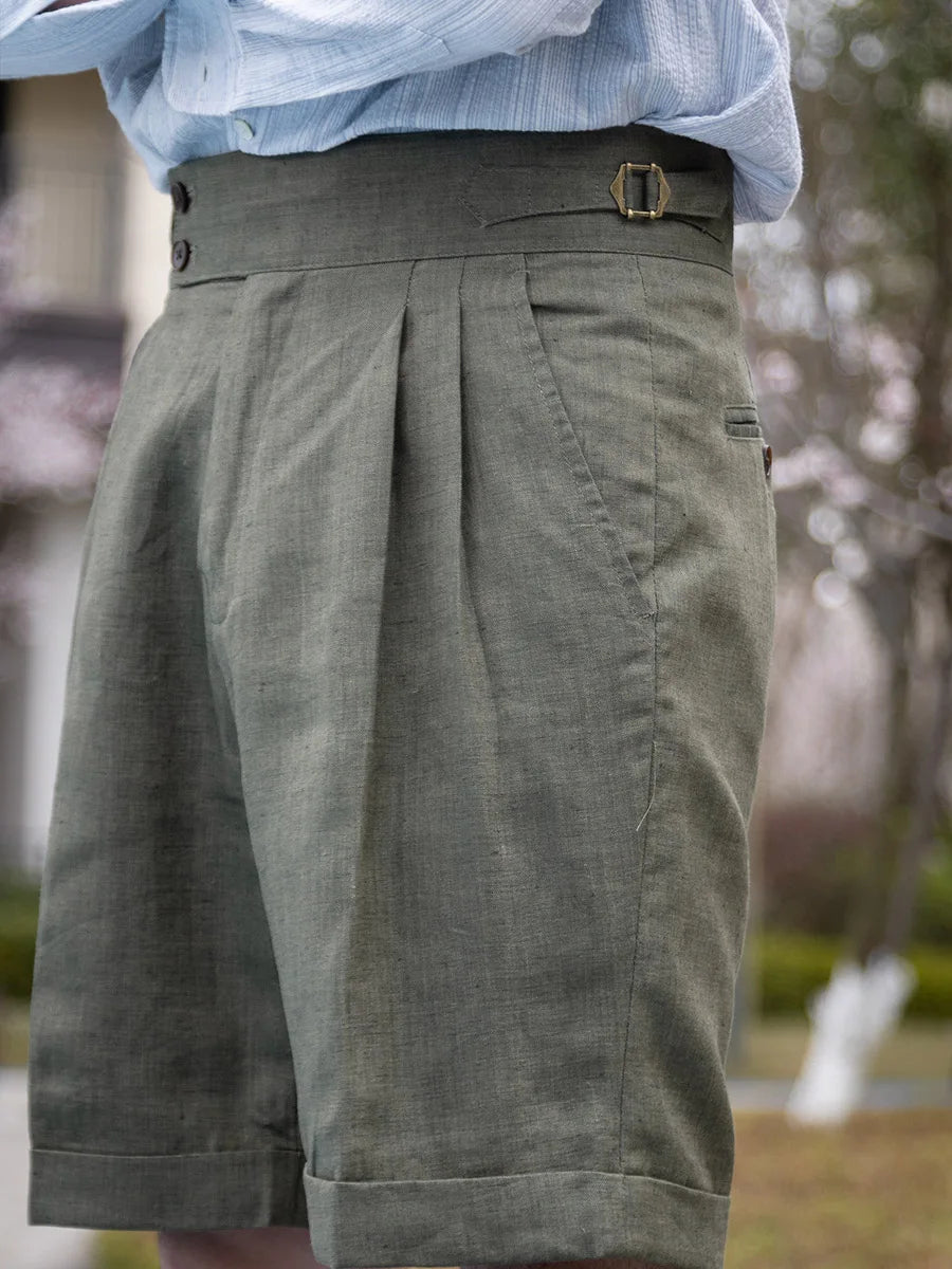 Model turned slightly to the left, offering a side view of the sage linen shorts with subtle pleats and refined tailoring. From Borcelleclothes.