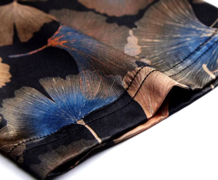 Detailed stitching and textured fabric on the sleeve of the Men's Nature-Inspired Mulberry Silk Shirt featuring an intricate ginkgo leaves pattern on a rich dark background, showcasing warm earthy shades and blue accents, symbolizing endurance and the beauty of changing seasons. From Borcelleclothes.