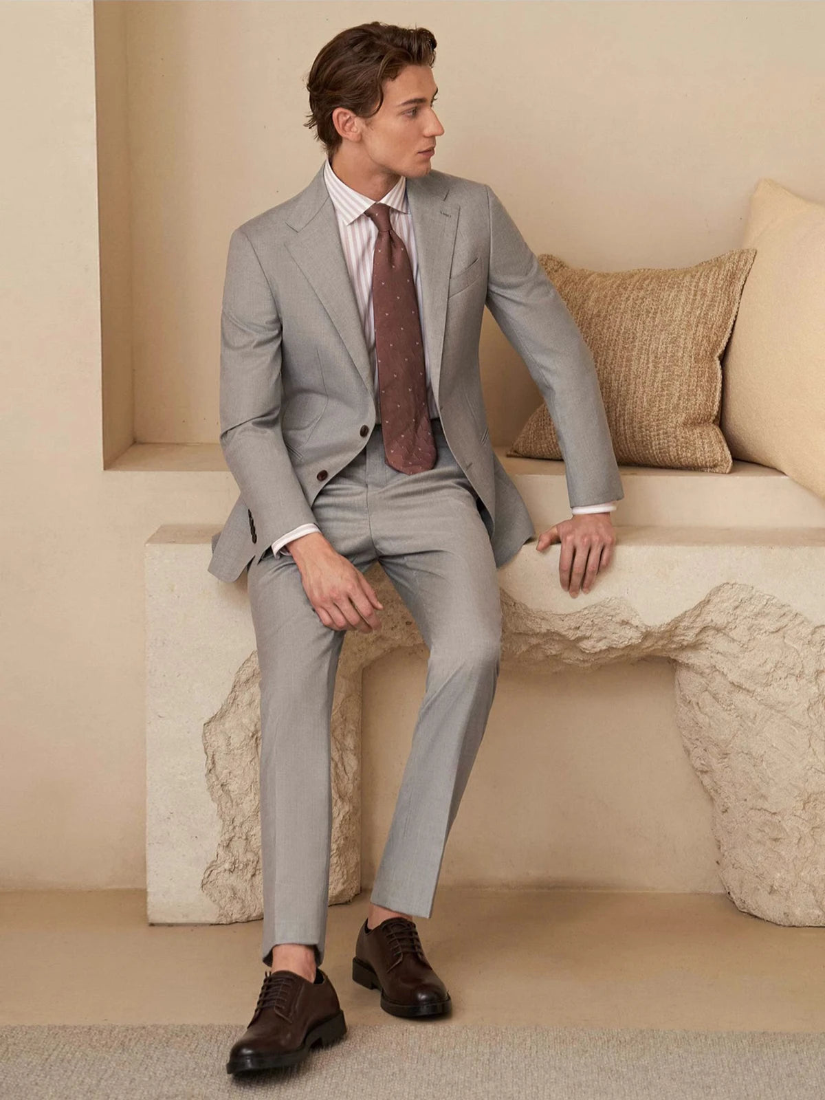 Man in the Nobel wool suit seated against a stone architectural background, blending classic tailoring with quiet elegance. From Borcelleclothes.