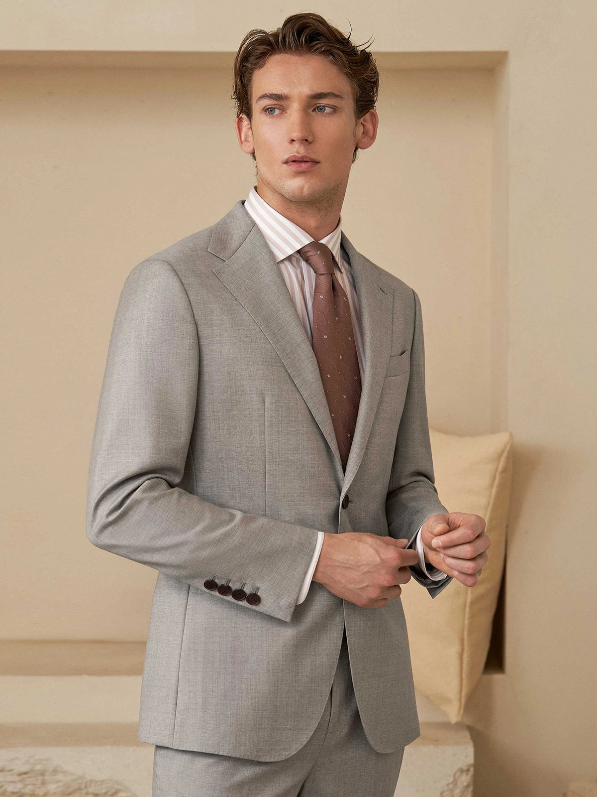 Model touches the sleeve placket of the blazer, highlighting handcrafted details and horn buttons. From Borcelleclothes.