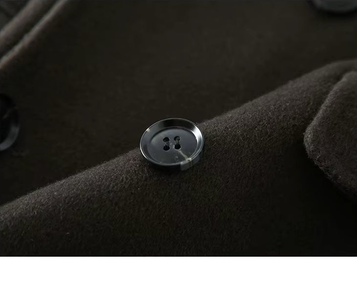 The button on the Men's Peaked-Lapel Wool Coat in Tuatara, showcasing its refined horn material and secure stitching. From Borcelleclothes.