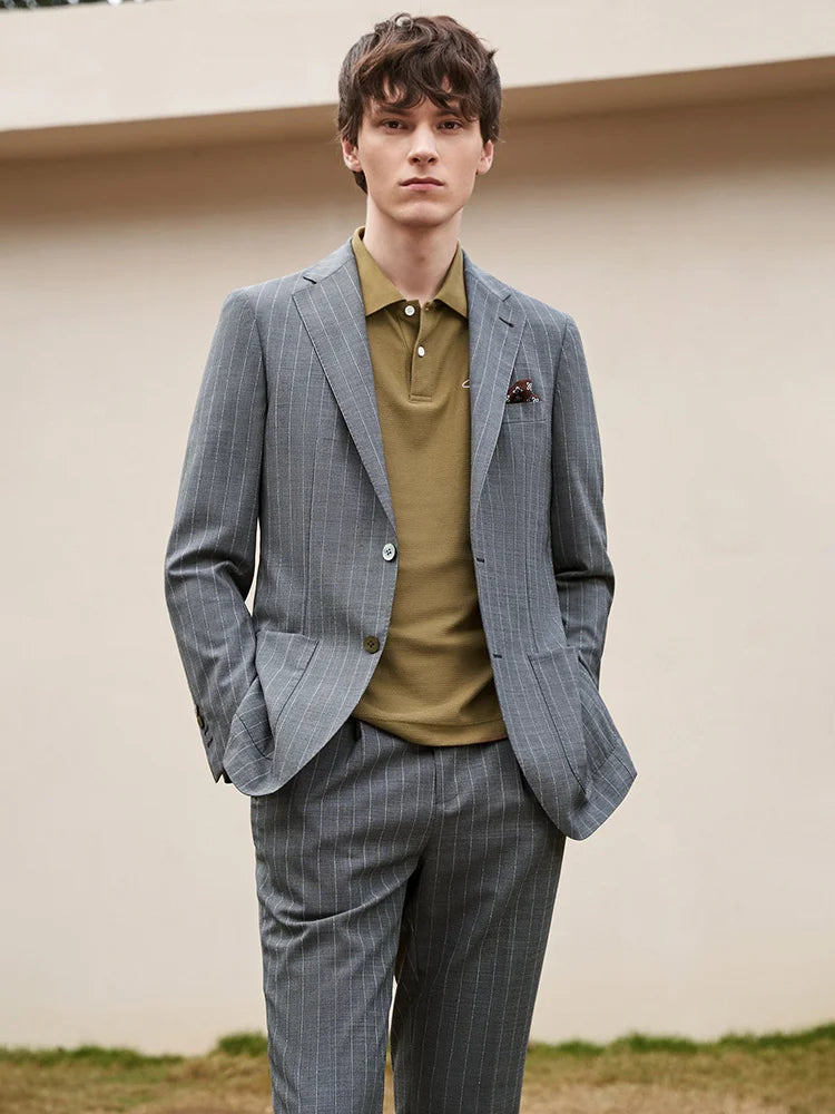 Storm Grey suit worn over olive polo shirt, with model’s hands tucked into pockets. A new take on formality. From Borcelleclothes.