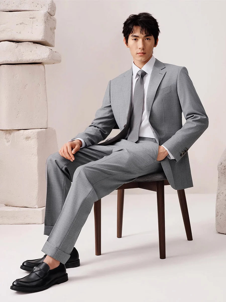 Men’s wool suit in French Grey with cuffed trousers, brown horn buttons, and notch lapels — a subtly textured, melange fabric suit evoking British tailoring with intellectual poise. From Borcelleclothes.
