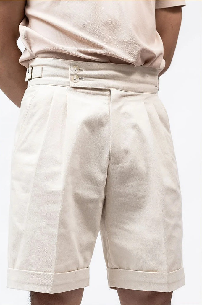 Model in Swiss Coffee shorts with hands behind back, emphasizing the shorts’ clean lines and quiet authority. From Borcelleclothes.