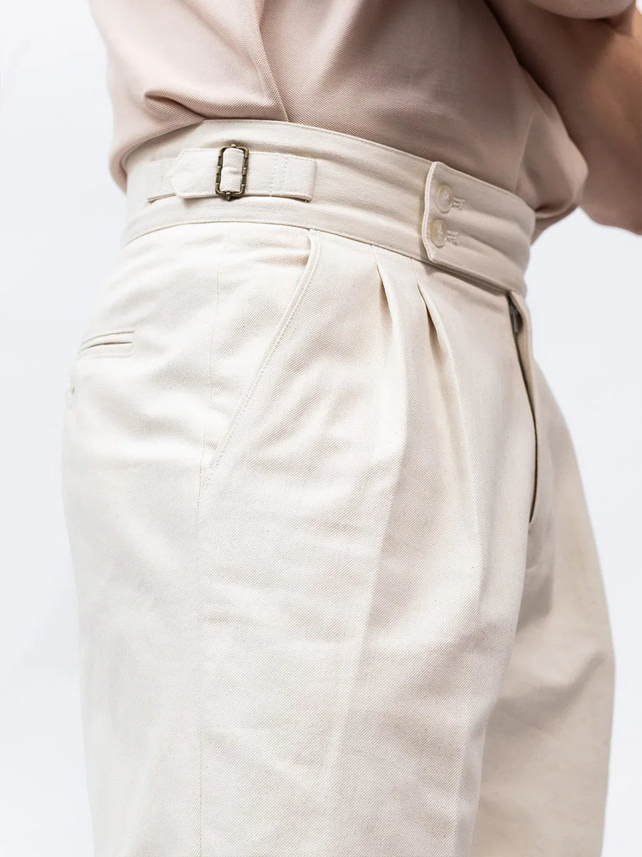 Side view of model in Swiss Coffee tailored shorts, showing front pleats and clean taper for a composed summer look. From Borcelleclothes.