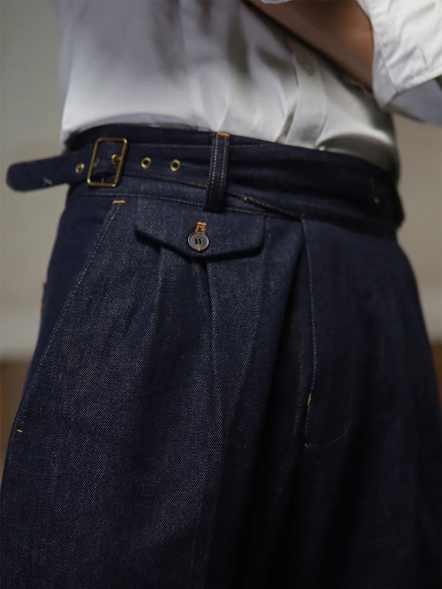 Close-up of the right waistband tab construction with brass buckle and grommet holes on the tailored denim trousers. From Borcelleclothes.