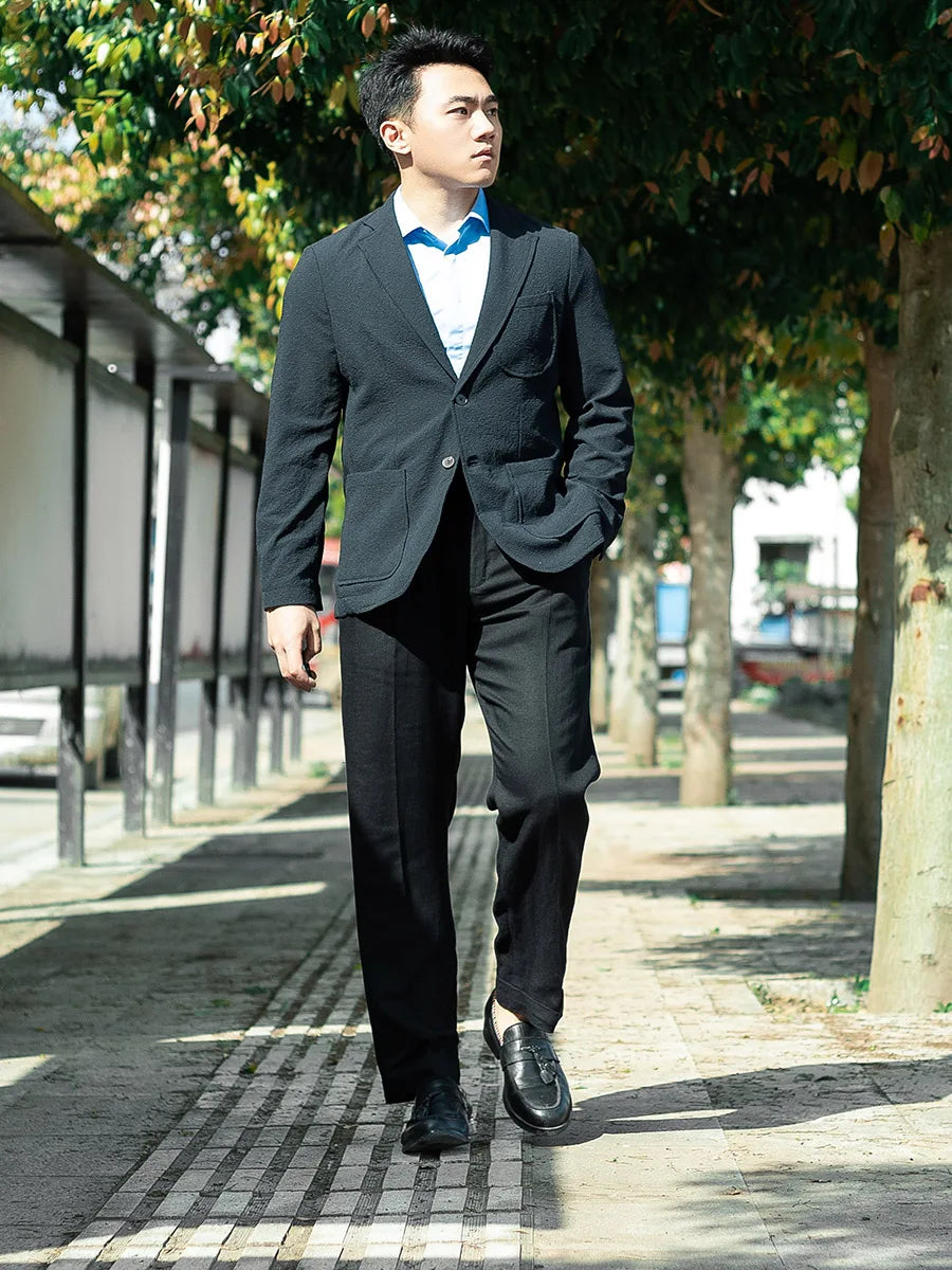 Model wearing tailored linen trousers in Onyx with hand in pocket, showcasing the clean front tucks and structured fit. From Borcelleclothes.