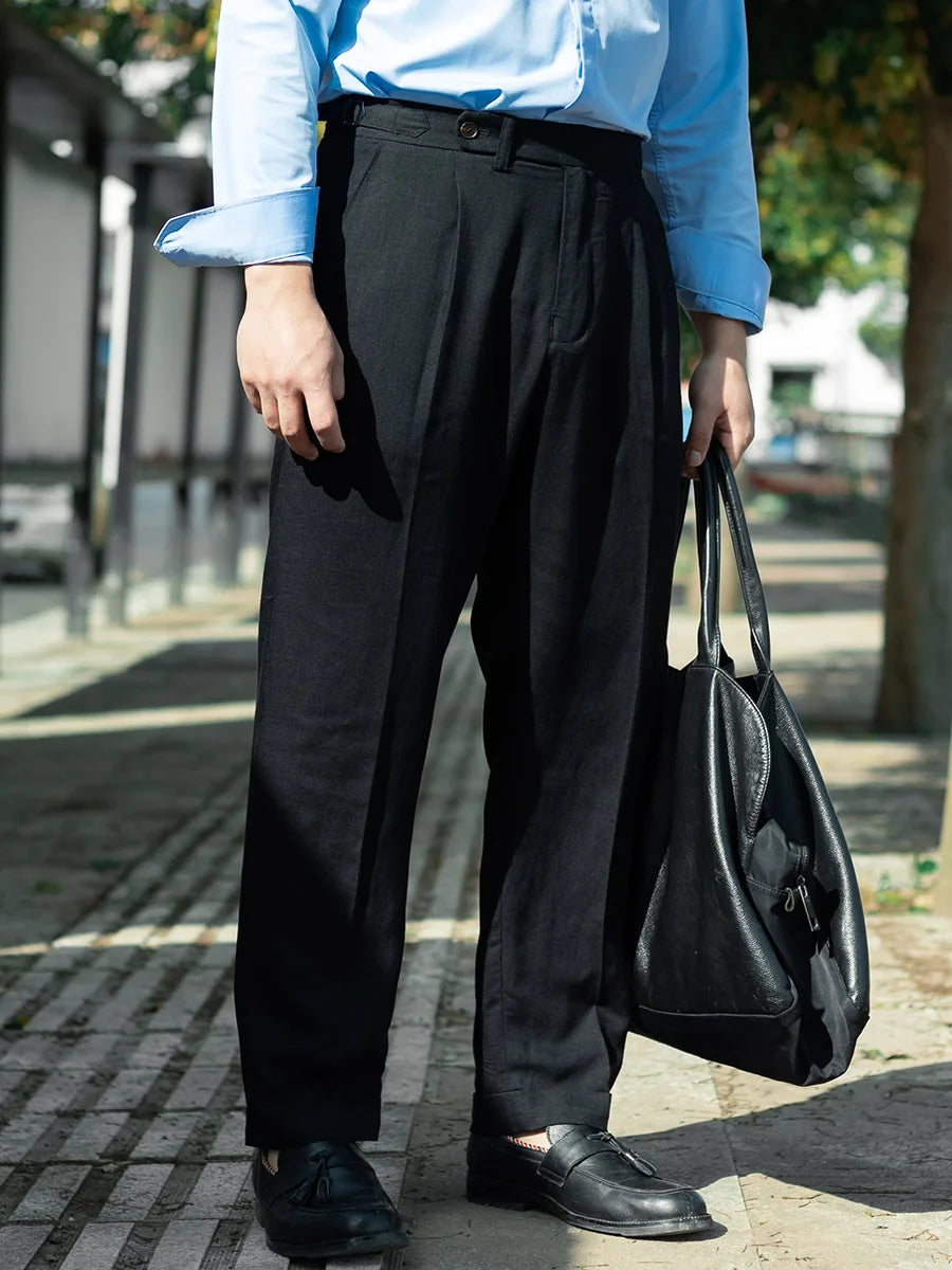 Model holding an oversized black bag while wearing Onyx linen trousers, showing off the cropped length and sharp silhouette. From Borcelleclothes.