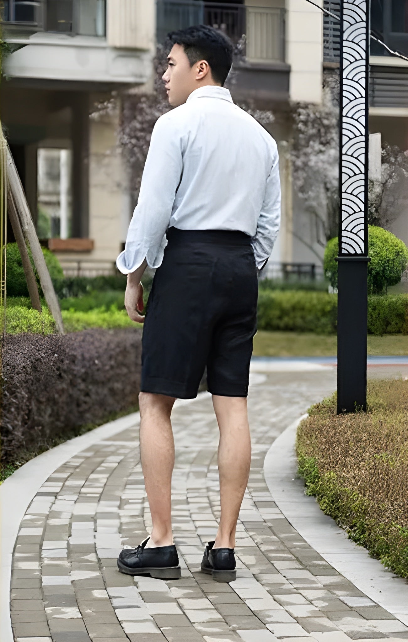 Rear view of the model in onyx linen tailored shorts, revealing the sharp back tailoring and smooth waistband. From Borcelleclothes.