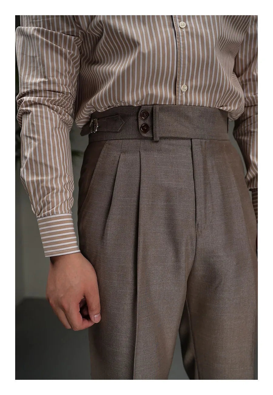 Upper front view of Wenge trousers highlighting front tucks, decorative loop, and waistband structure. From Borcelleclothes.