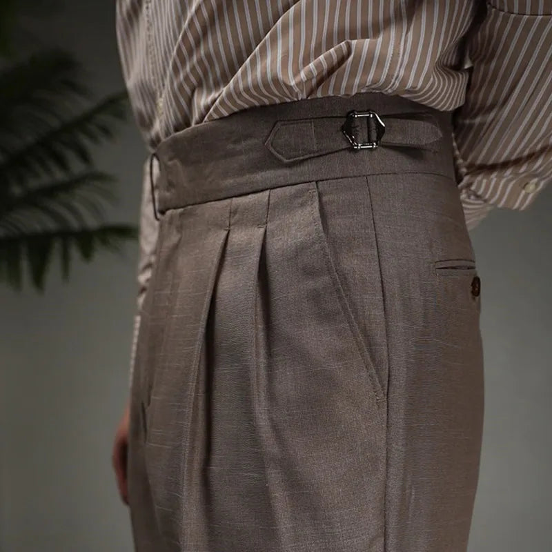 Upper left side view of Wenge trousers, showing waistband, pleats, and side tab details. From Borcelleclothes.
