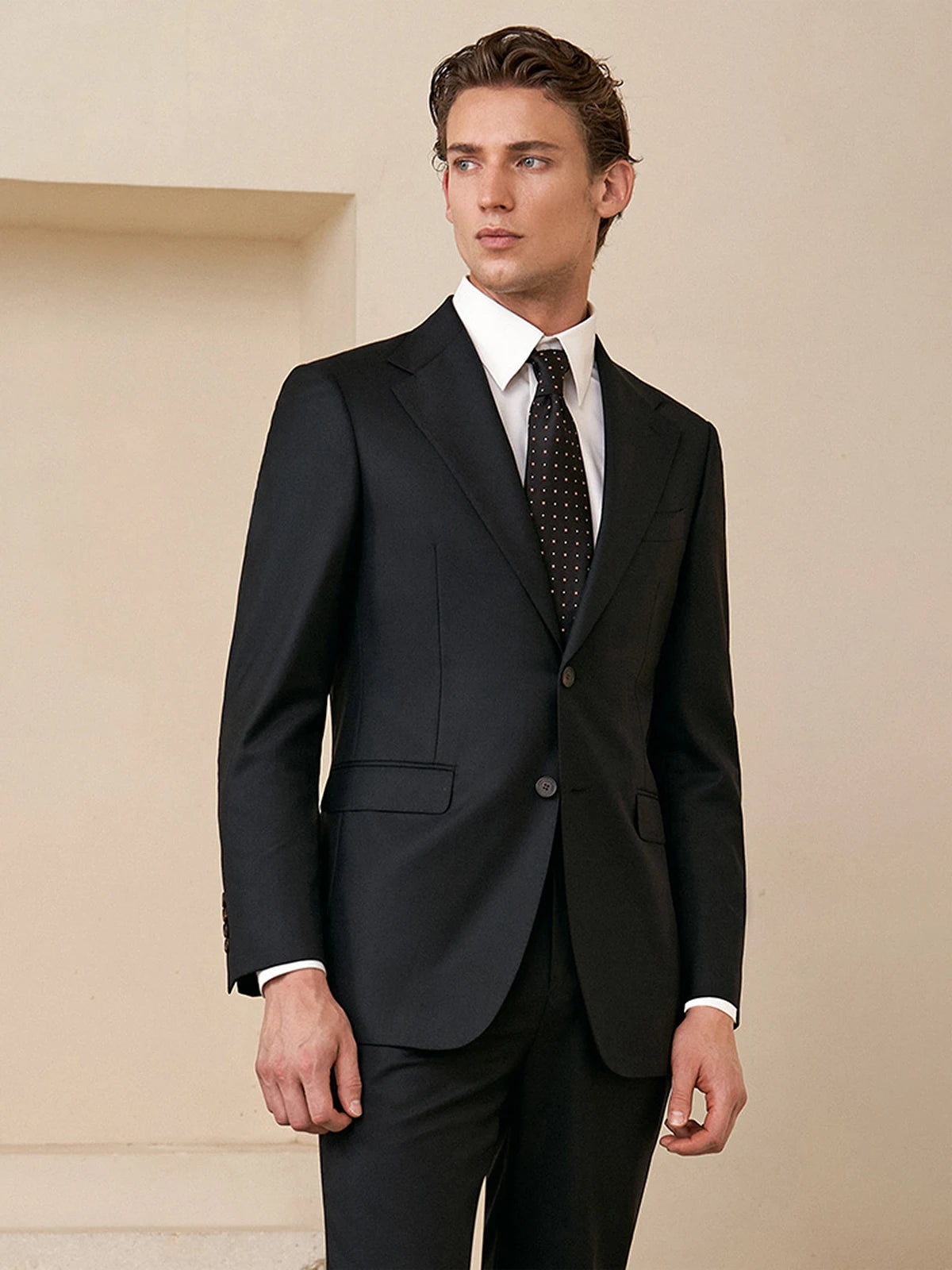 Model in the Borcelleclothes Men's Wool and Silk Blend Suit in Onyx Texture, turned slightly to the side, showing the streamlined tailoring and structured silhouette.