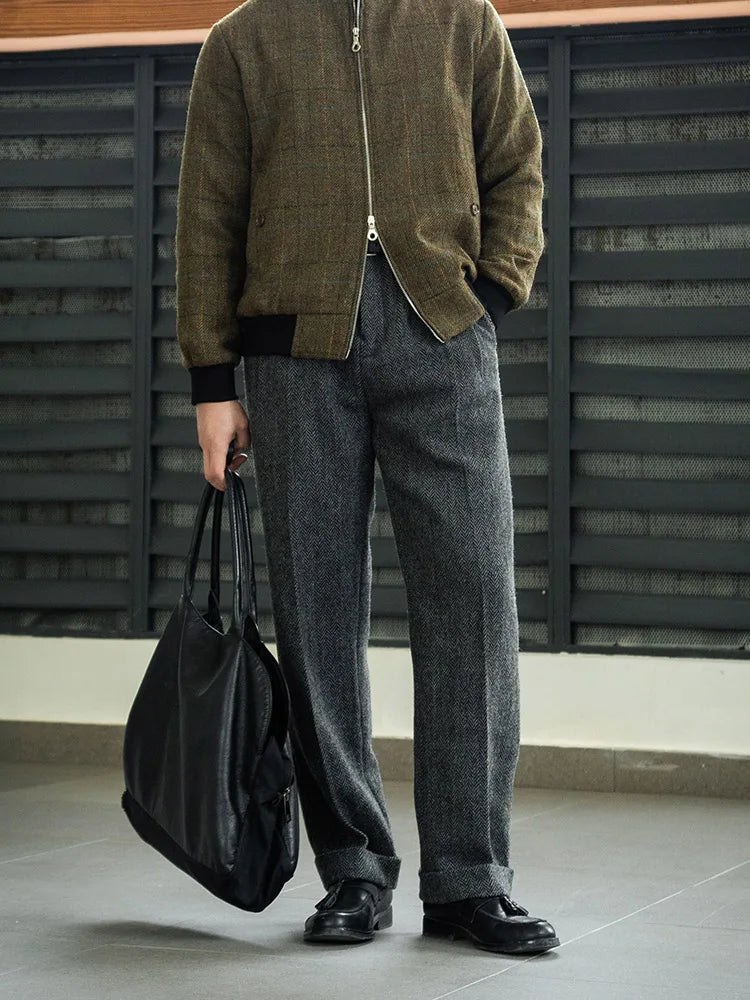 Man in Oslo Grey wool tweed trousers holding a leather bag, showcasing the relaxed drape and pleated front. From Borcelleclothes.