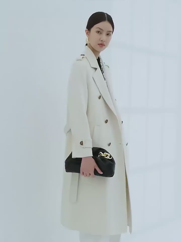 Video showcasing a Women's Grade A Cashmere Coat in Floral White—crafted from 100% double-sided Grade A cashmere for unmatched softness and refinement. Featuring a double-breasted silhouette, embossed buttons, shoulder tabs, and decorative sleeve details, this mid-calf coat embodies timeless elegance and commanding presence. From Borcelleclothes.