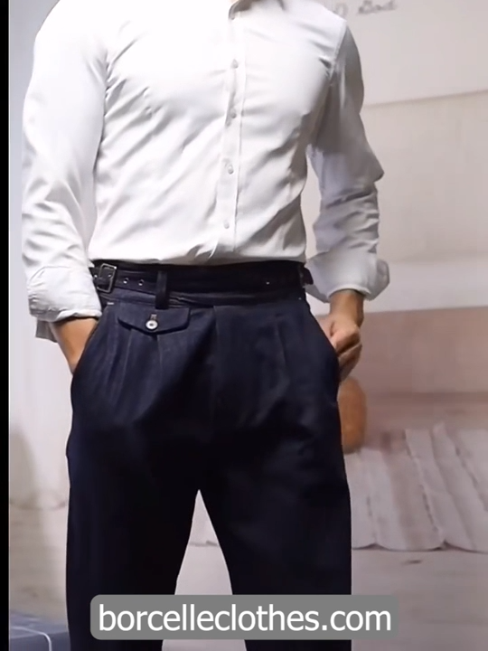 Video showcasing a Men's tailored denim trousers in Midnight Express with four front pleats, dual side buckles, and contrast stitching. From Borcelleclothes.