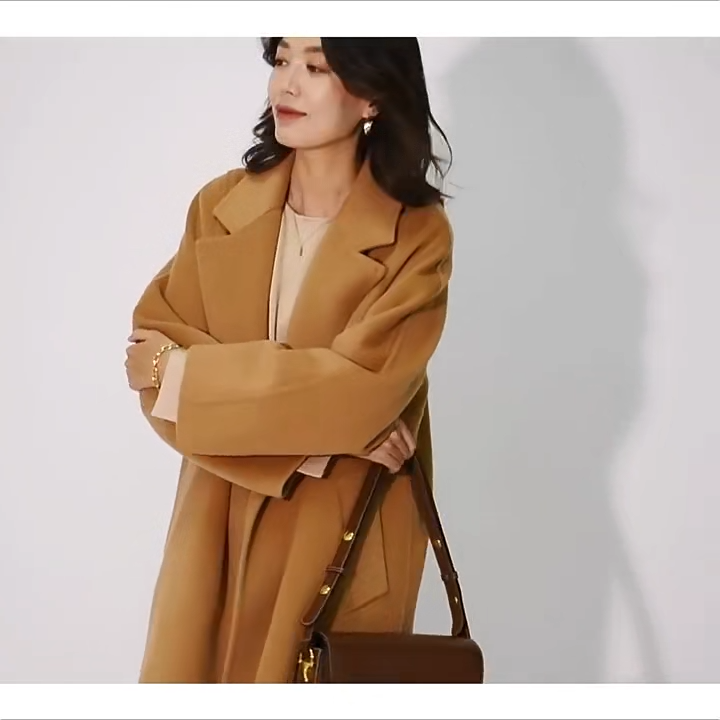 Video showcsing a Women's Wrap Coat Redefined in all colors—crafted from a luxurious blend of Merino wool and cashmere. Featuring square gussets for a structured silhouette, notch lapels, a single-welt pocket design, and an adjustable belt, this mid-calf wrap coat blends modern tailoring with timeless elegance. From Borcelleclothes.