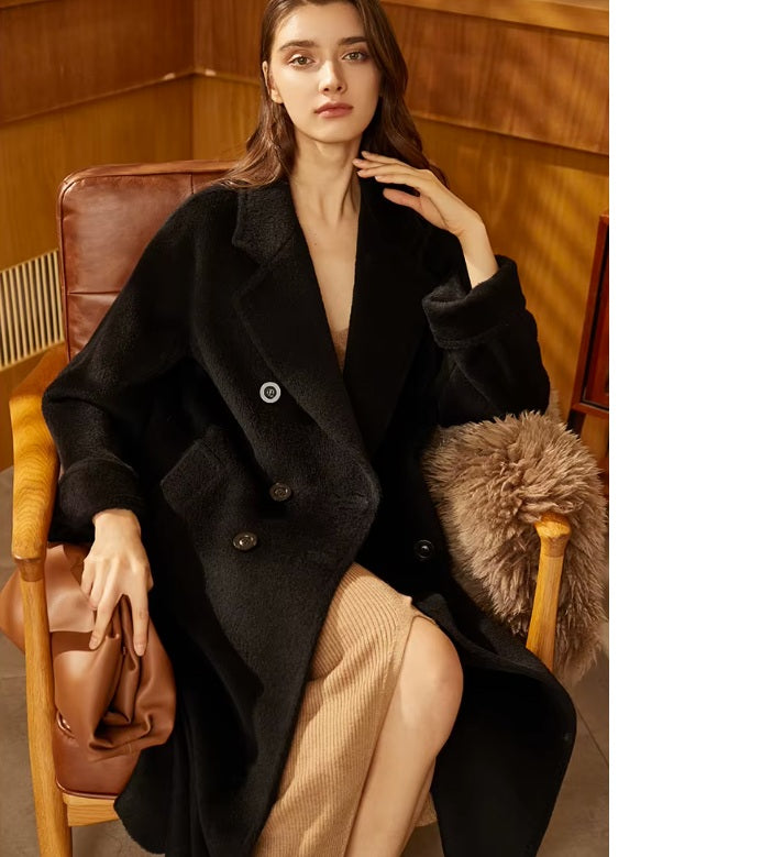 Model wearing the Women’s Mid-Calf Alpaca Coat in Onyx, gently touching their neck, highlighting the luxurious texture and timeless color. From Borcelleclothes.