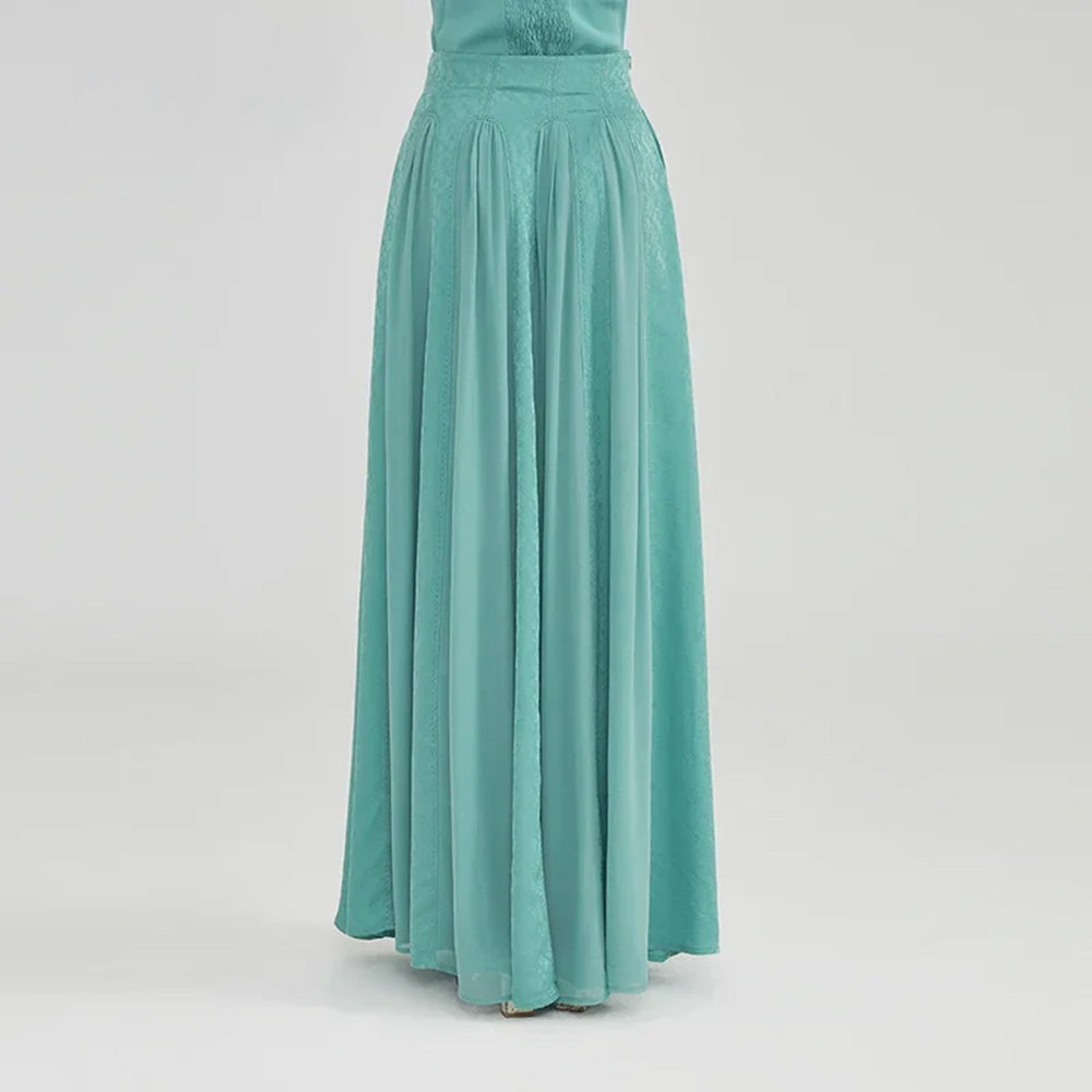 A distant, cinematic back view of the model walking away, highlighting the grand, enveloping volume of the silk maxi skirt's trailing hem — From Borcelleclothes.