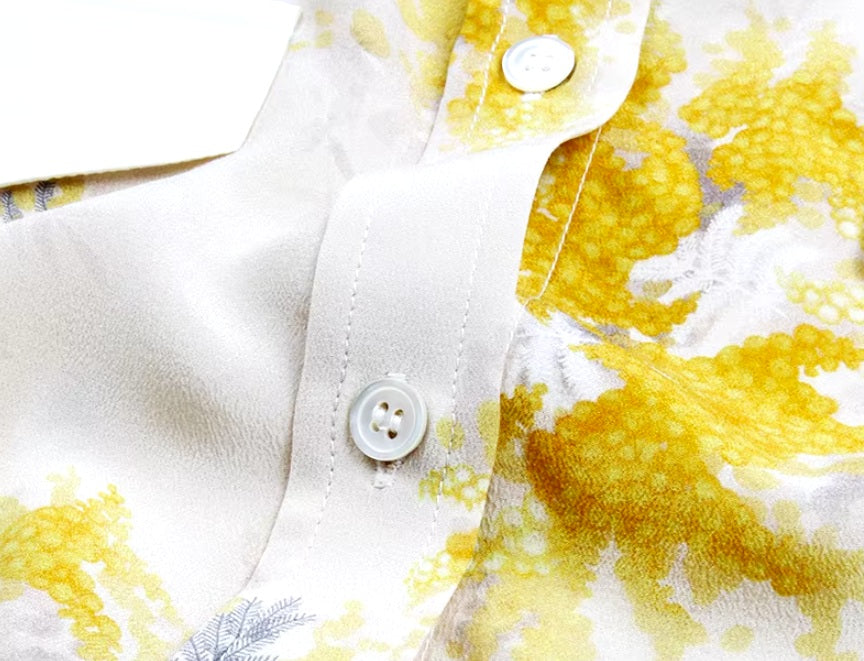 Detailed stitching and textured fabric on the part of the placket of a Women's 100% Mulberry Silk Shirt with Mimosa Print in Dawn Pink, featuring contrast collar, bold accents, and a flowing silhouette. From Borcelleclothes.